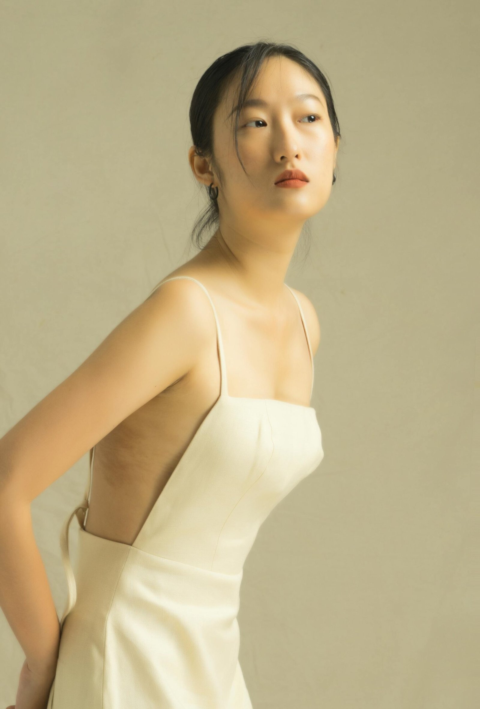 Graceful portrait of an Asian woman in a beige dress, showcasing elegance and fashion.